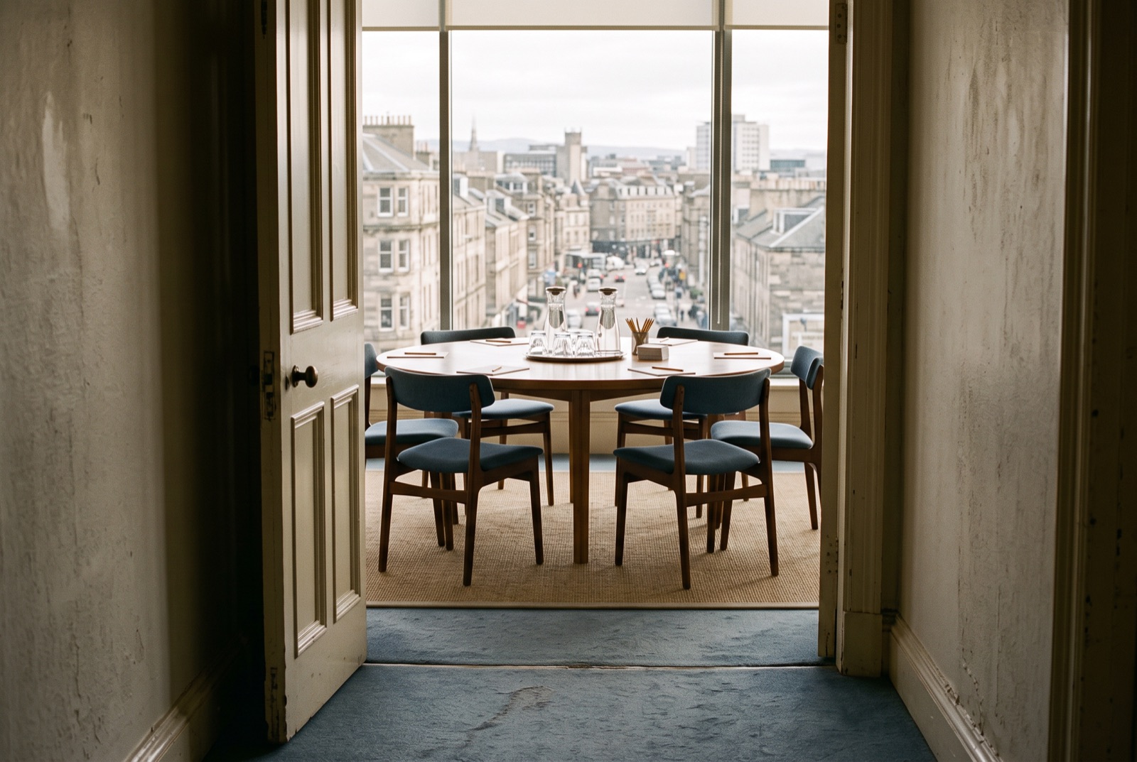A forum room with a round table, carafes and a view of a city