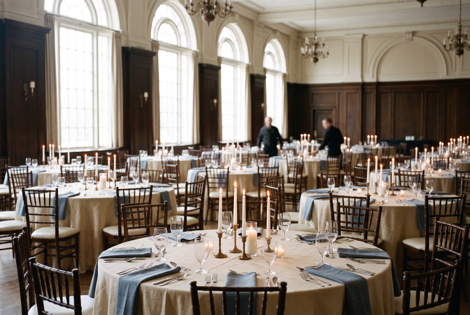 A gala hall with round tables and candlelight before guests arrive