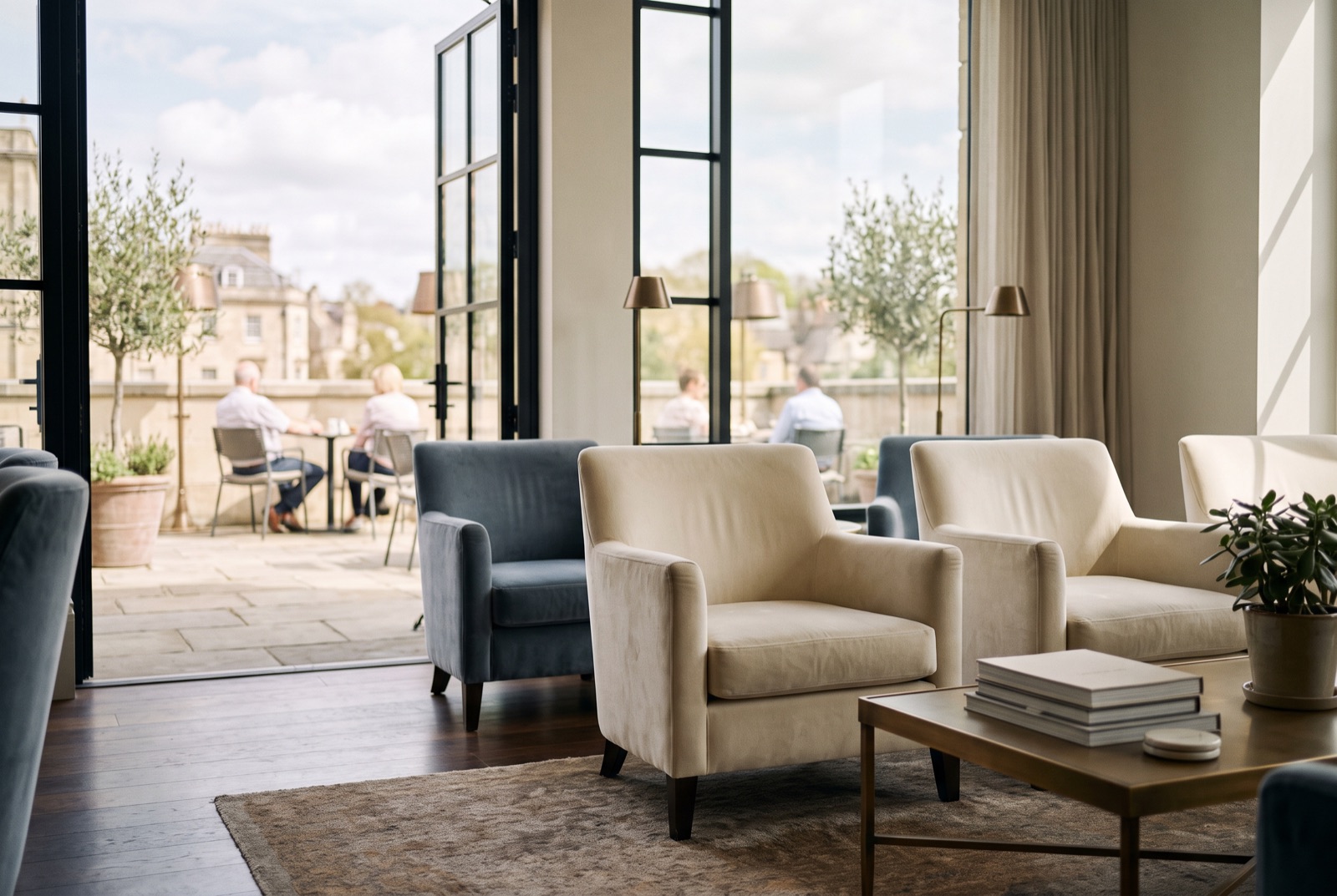 A bright members' lounge with velvet chairs opening onto a terrace