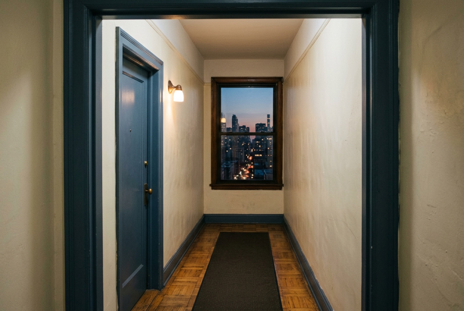 A corridor with a single closed door and a soft lamp