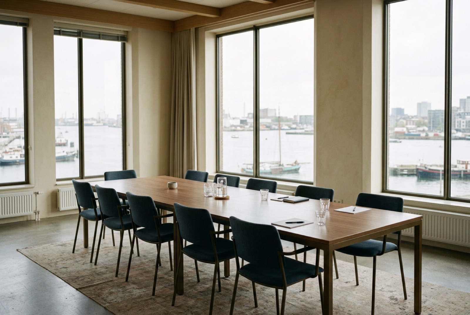 A conference table by tall windows with the chairs pushed in after a session