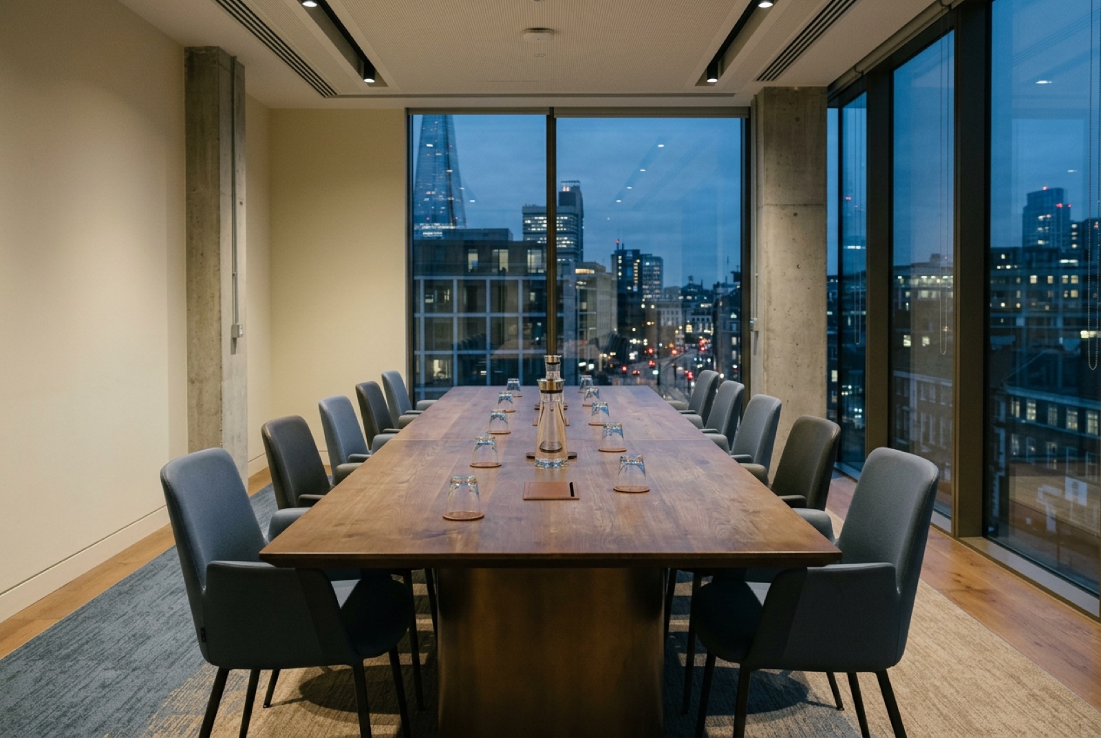 A conference table by tall windows with the chairs pushed in after a session