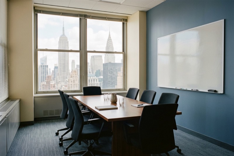 A small private meeting room with a wiped whiteboard and eight chairs