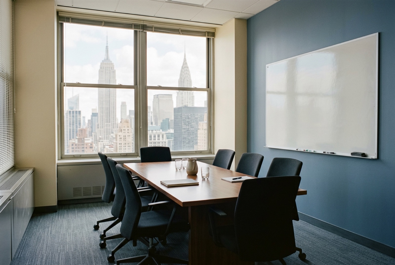 A small private meeting room with a wiped whiteboard and eight chairs