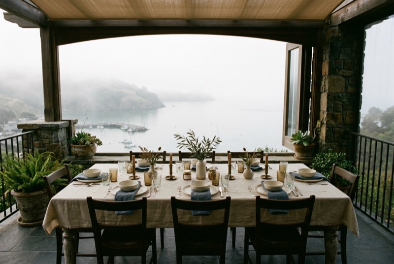 A terrace dinner table set for eight above a harbour
