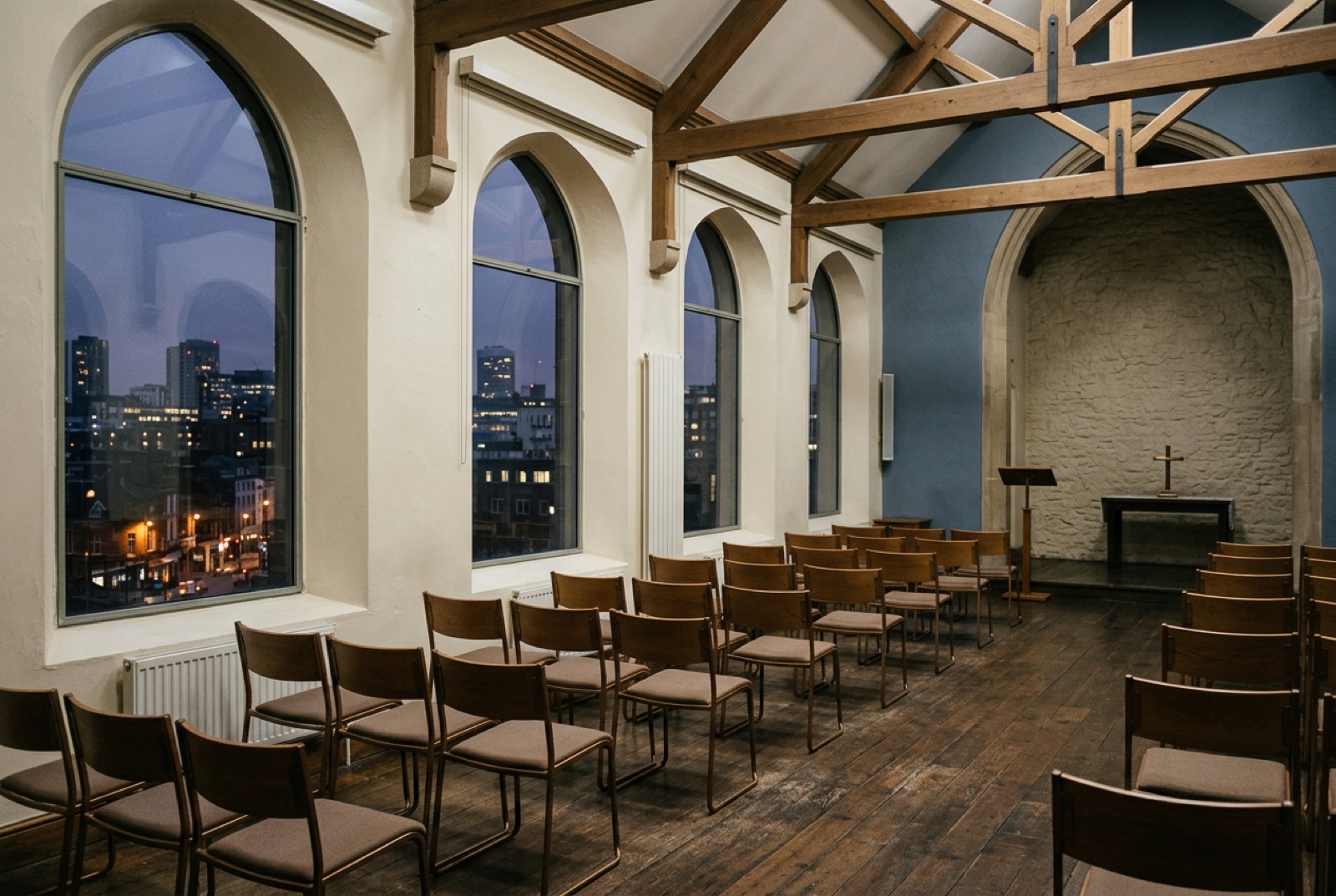A chapel-like hall with tall windows and rows of chairs