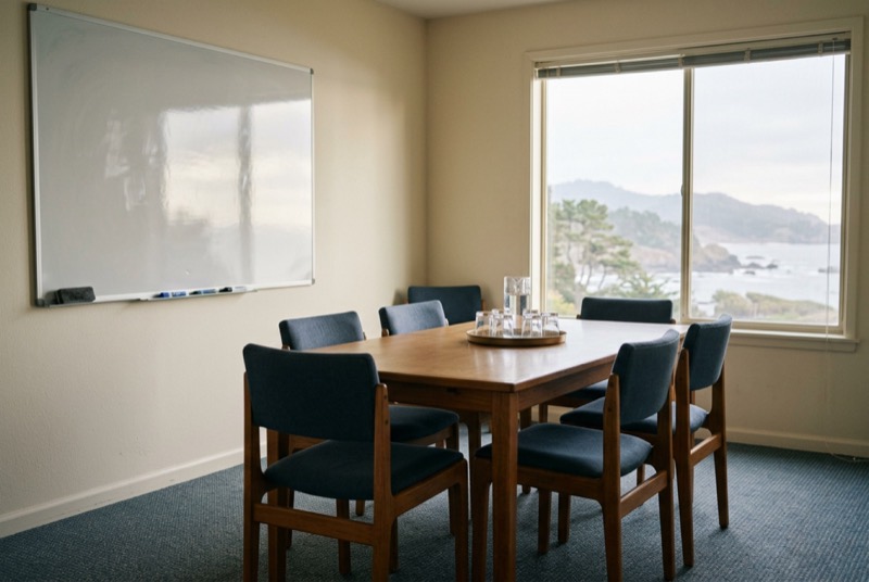 A small private meeting room with a wiped whiteboard and eight chairs